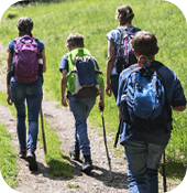 Children walking on hiking path with adult on a sunny day