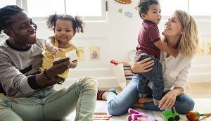 Parents and their small children playing on the floor with toys