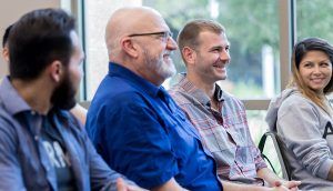Group of people smiling and sharing stories during a group meeting at a center