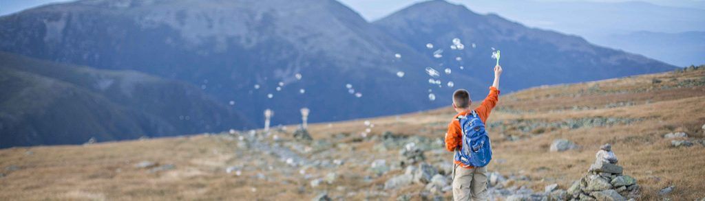 Young boy blowing bubbles while hiking at Mount Washington State Park, New Hampshire