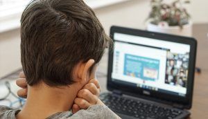 A boy looking at a laptop computer with an online learning system on the screen.