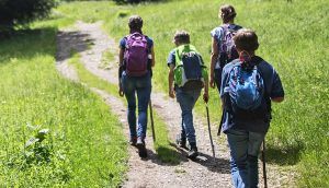 Children walking on hiking path with adult on a sunny day